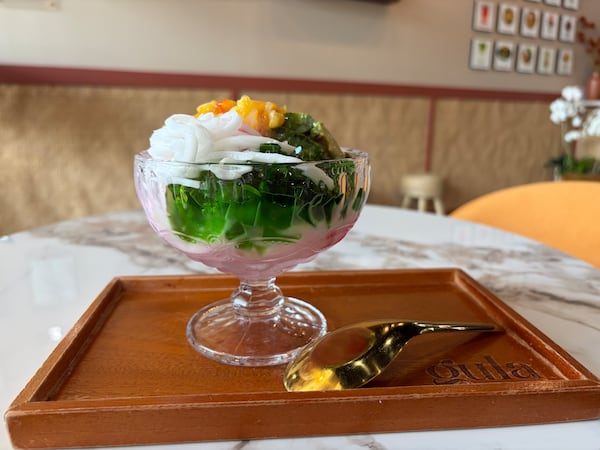 A straight-ahead look at a glass dish filled with an Indonesian dessert called es campur, shaved ice that is topped with avocado, coconut, jackfruit and condensed milk.