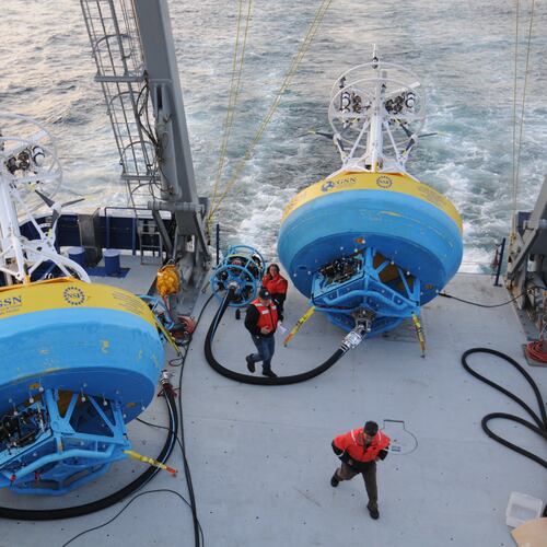 In this 2021 image provided by Woods Hole Oceanographic Institution, workers walk near buoys used to gather data at Pioneer New England shelf off the coast of Martha’s Vineyard, Mass. (Véronique LaCapra/Woods Hole Oceanographic Institution via AP)