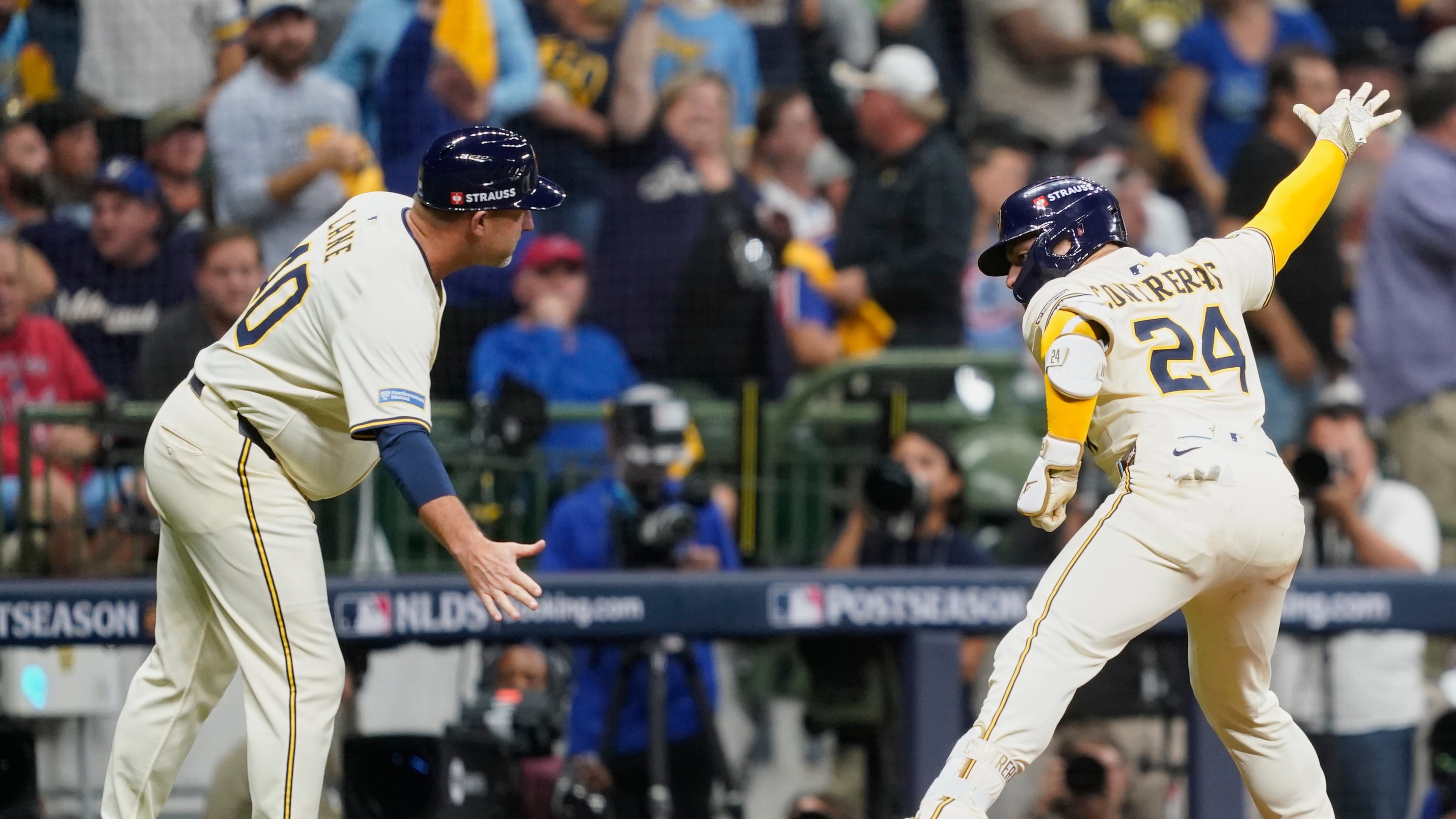 Milwaukee Brewers' William Contreras (24) celebrates with third base coach Jason Lane (40) after hitting a solo home run during the third inning of Game 2 of baseball's National League Division Series against the Chicago Cubs Monday, Oct. 6, 2025, in Milwaukee. (AP Photo/Kayla Wolf)