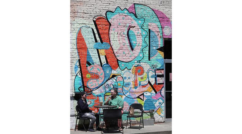 Mallory Lunquist (left) and Dan Merewether enjoy their coffee orders outdoors at the Hodgepodge Coffeehouse on Thursday, April 22, 2021, in Atlanta.     Curtis Compton / Curtis.Compton@ajc.com