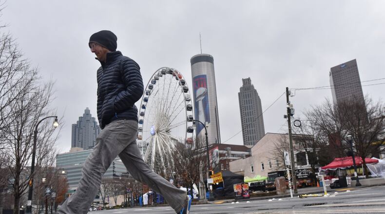 A pedestrian crosses the street in downtown Atlanta Tuesday as the weather improved. State transportaton officials are still cautioning motorists about Wednesday morning’s commute. “Sun and wind are playing in our favor,” Georgia Department of Transportation spokeswoman Natalie Dale said. “Any remaining moisture may lead to patchy black ice, so we encourage safe and slow travel in the morning.” HYOSUB SHIN / HSHIN@AJC.COM