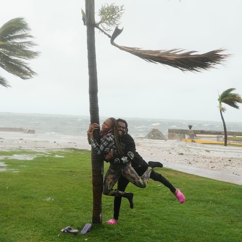 A couple jokes around on the coast in Kingston, Jamaica, as Hurricane Melissa approaches, Tuesday, Oct. 28, 2025. (AP Photo/Matias Delacroix)