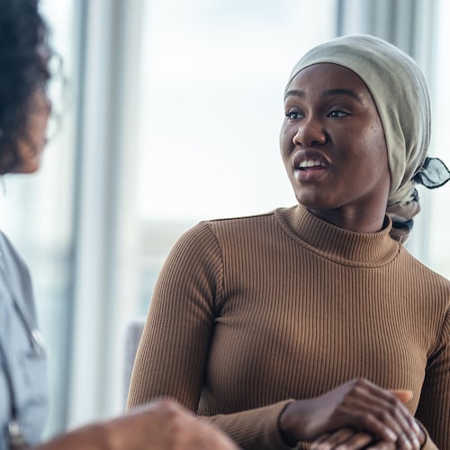 A young black woman with cancer is consulting her doctor. She is wearing a bandana to hide her hair loss. While mortality rates are declining, some cancers are more frequently diagnosed in younger Americans, and that should have us concerned.