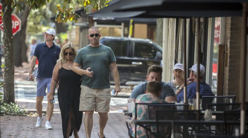 A couple walks past the Six Pence restaurant on Bull Street in the Historic Downtown Savannah. Savannah became the first major city in Georgia to require the use of face masks, setting up a potential showdown with Gov. Brian Kemp over whether local officials can take more sweeping steps than the state to contain the coronavirus. (AJC Photo/Stephen B. Morton)