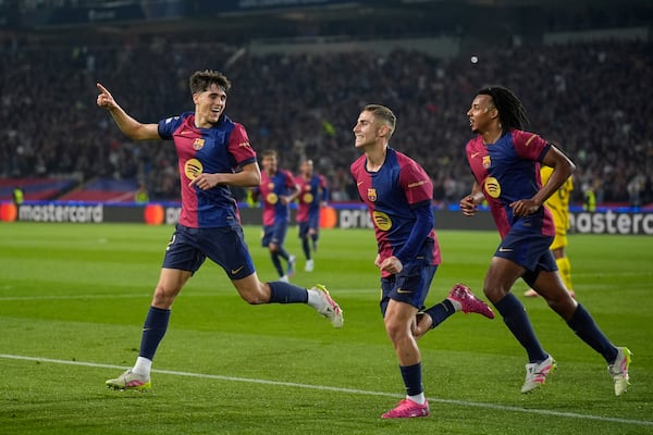 Barcelona's Pau Cubarsi, left, Barcelona's Fermin Lopez, center, and Barcelona's Jules Kounde celebrate after their teammate Raphinha, left, scores his side's opening goal during the Champions League quarterfinal first leg soccer match between Barcelona and Borussia Dortmund, at the Lluis Companys Olympic stadium in Barcelona, Spain, Wednesday, April 9, 2025. (AP Photo/Emilio Morenatti)
