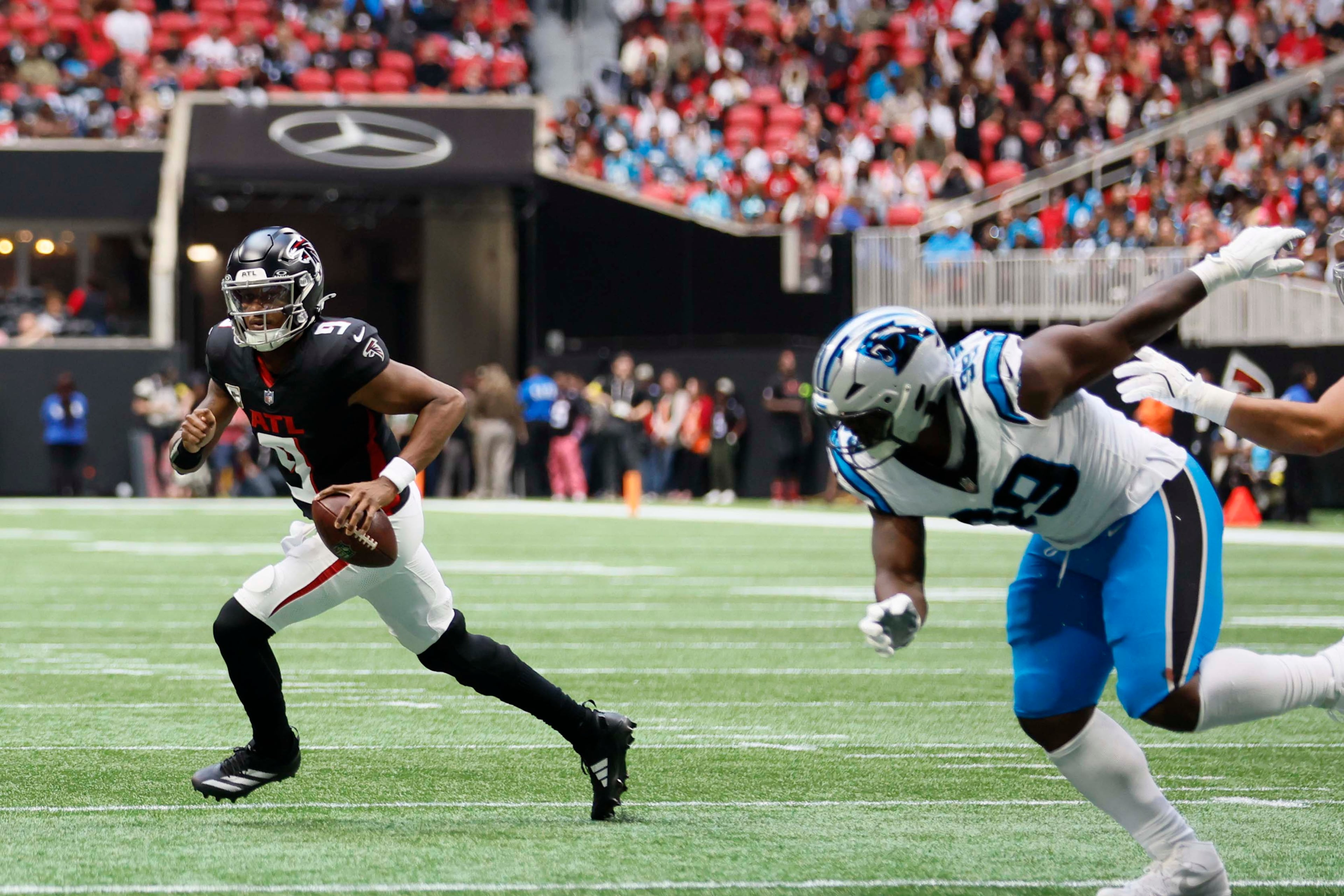 Atlanta Falcons quarterback Michael Penix Jr. (left) escapes the pocket during the first half of an NFL football game against the Carolina Panthers at Mercedes-Benz Stadium in Atlanta on Sunday, Nov. 16, 2025. (Miguel Martinez/AJC)