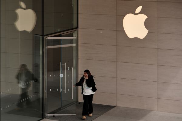A woman walks out from an Apple Store at an outdoor shopping mall in Beijing, Tuesday, April 8, 2025. (AP Photo/Andy Wong)