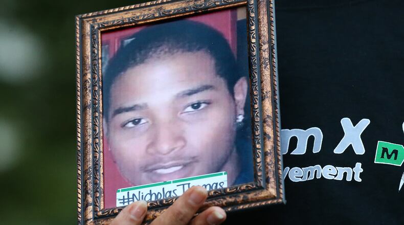 A demonstrator holds a photograph of Nicholas Thomas, one of several that activists believe have died needlessly, during a protest at the Fulton County Courthouse on Tuesday, Aug. 30, 2016, in Atlanta. Curtis Compton /ccompton@ajc.com