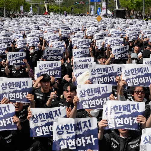 Members of the Samsung Electronics labor union hold up their cards during a rally demanding higher bonuses at its computer chip complex in Pyeongtaek, South Korea, Thursday, April 23, 2026. The letters read "Remove the bonuses caps." (AP Photo/Ahn Young-joon)