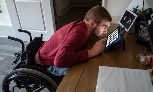 Matt Thompson work with his computer table assistant in his room at Champions Place. PHIL SKINNER FOR THE ATLANTA JOURNAL-CONSTITUTION.