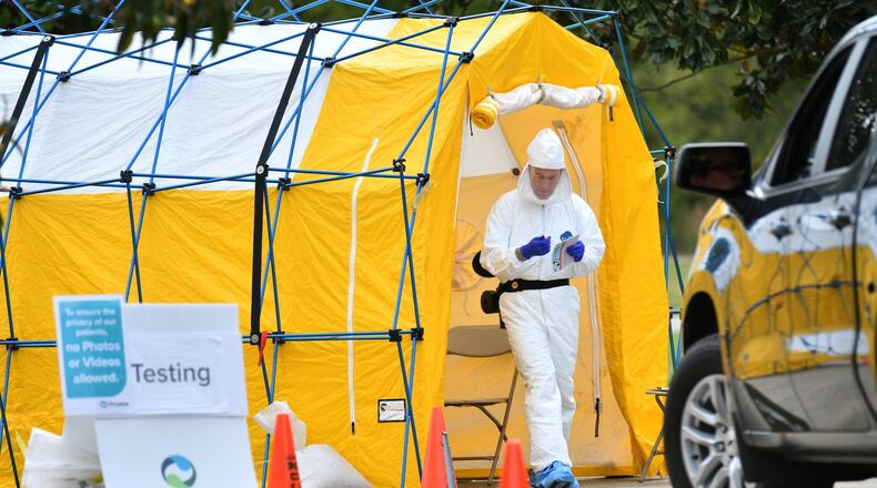 A medical professional in protective gear prepares to collect a sample from a potential COVID-19 patient at a Phoebe Putney Health System drive-through testing site in Albany. (Hyosub Shin / Hyosub.Shin@ajc.com)