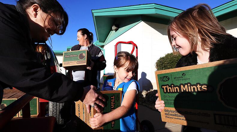 Daisy Samantha Weathers, center, and Brownie Madeline Taylor help bring out cases of cookies to Tatum Roe, volunteer product sales committee member with the Girl Scouts of the Desert Southwest, as she stacks them on a trailer bed for the 41018 troop which has 381 cases of cookies for the start of the Girl Scout Cookie Sale Program.