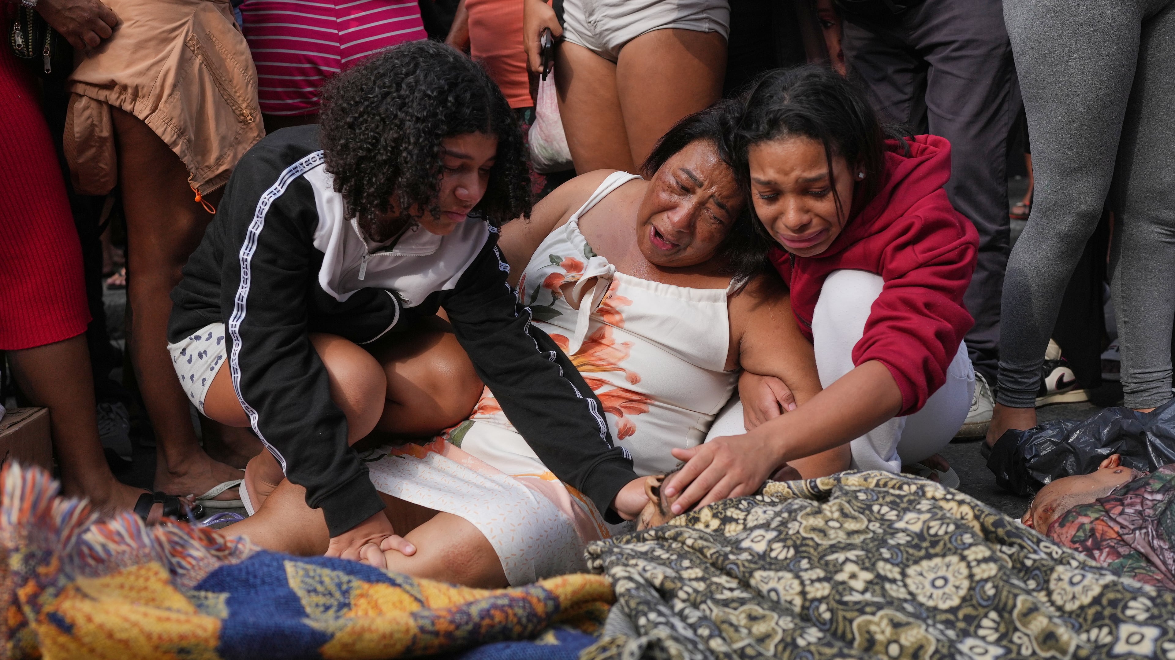 Relatives mourn over the bodies of people killed the day before during a police raid targeting the Comando Vermelho gang in the Complexo da Penha favela of Rio de Janeiro, Brazil, Wednesday, Oct. 29, 2025. (AP Photo/Silvia Izquierdo)