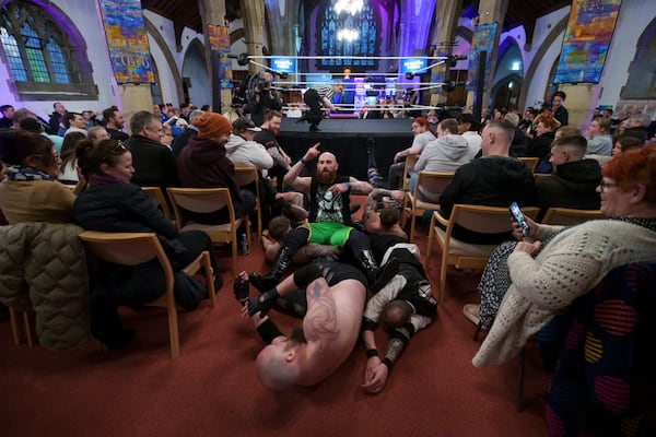 A six-man-scramble spills out of the ring at a Kingdom Wrestling show at St Peter's Church in Shipley, Saturday, March 29, 2025. (AP Photo/Jon Super)