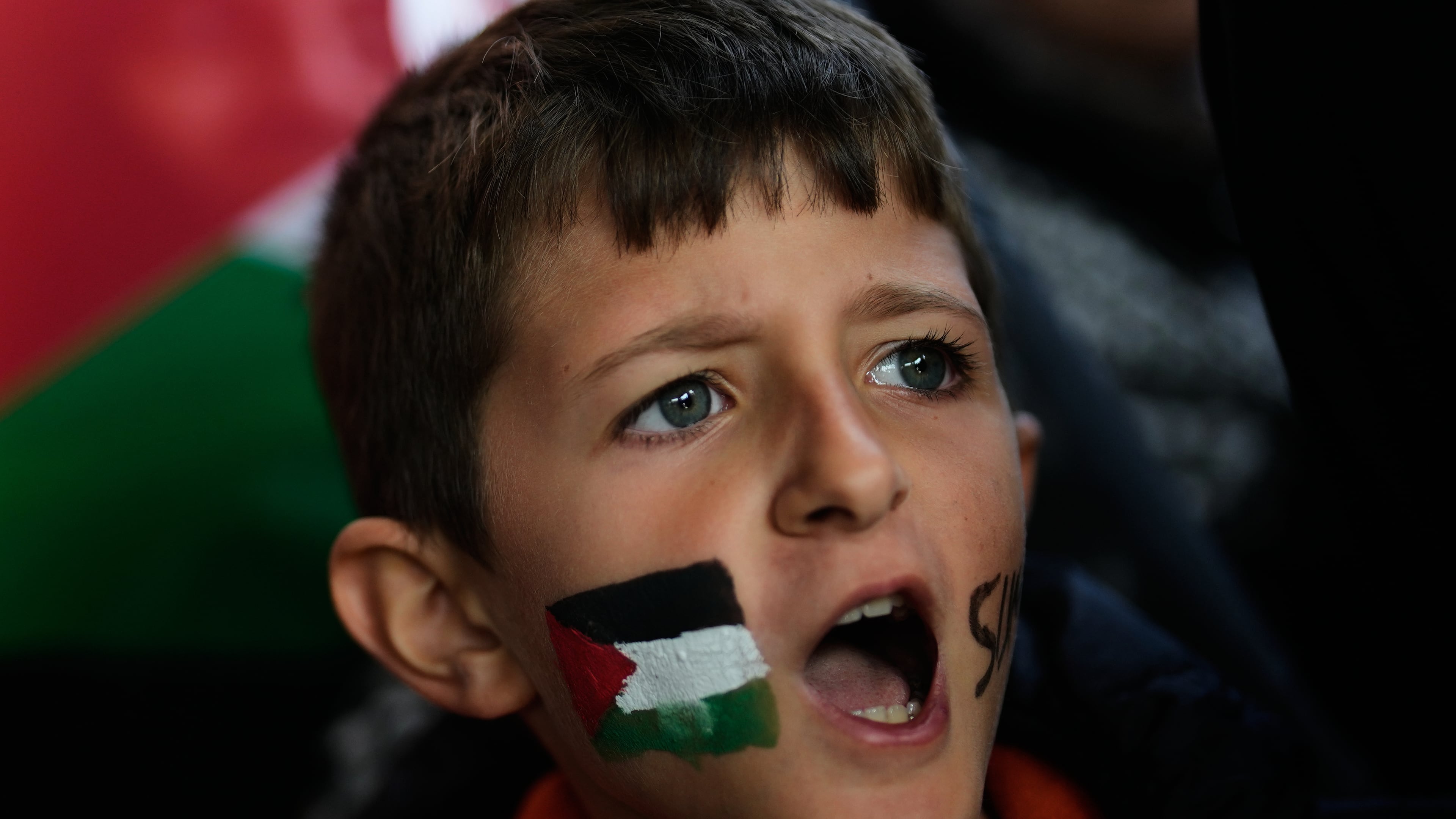 A boy with a Palestinian flag painted on his face chants slogans during a gathering outside Istanbul Airport, as people wait for the arrival of 137 activists from the Global Sumud Flotilla, in Istanbul, Turkey, Saturday, Oct. 4, 2025. (AP Photo/Khalil Hamra)