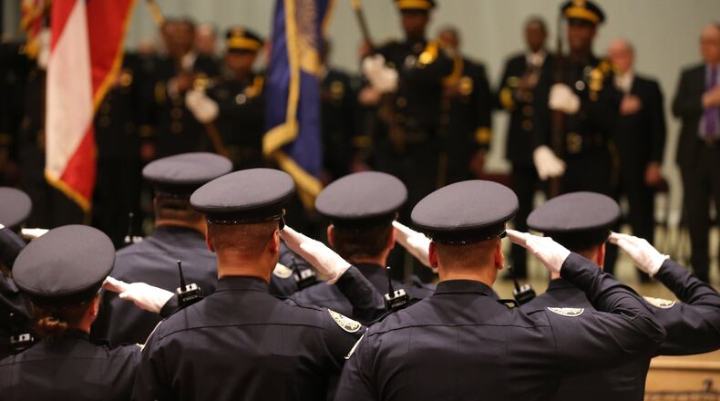 March 18, 2015 Atlanta: Atlanta Police recruits salute during the presentation of colors before their graduation ceremony Wednesday evening March 18, 2015 at North Atlanta High School. Ben Gray / bgray@ajc.com