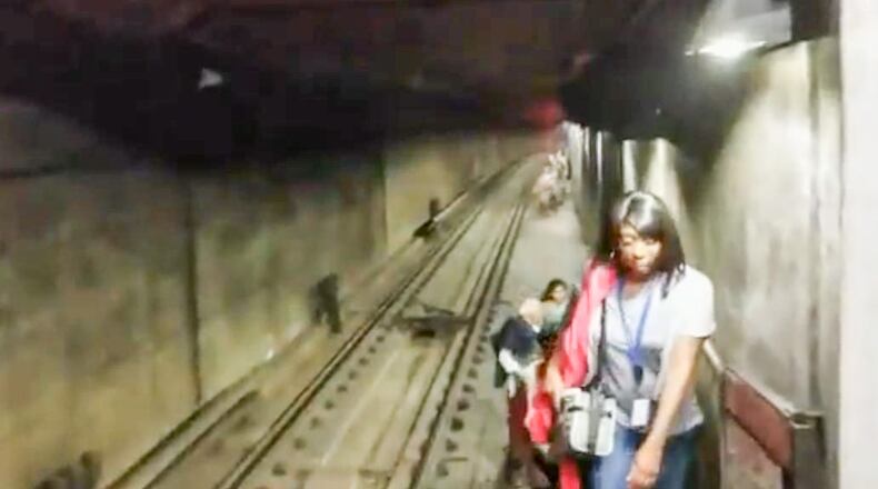 MARTA passengers walk through a tunnel after climbing out of a stalled train car near the Arts Center station on Wednesday night.