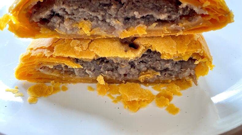 The classic Jamaican beef patty at Belle & Lily's Caribbean Brunch House is a warm hit of spice enveloped in buttery layers of flaky shell. Angela Hansberger for The Atlanta Journal-Constitution