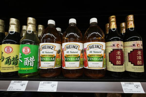 Bottles of Mature Donghu vinegar imported from China, right, sit next to Heinz US made All Natural Apple Cider vinegar in an aisle at 99 Ranch Market, an Asian grocery store in Los Angeles Monday, April 7, 2025. (AP Photo/Damian Dovarganes)