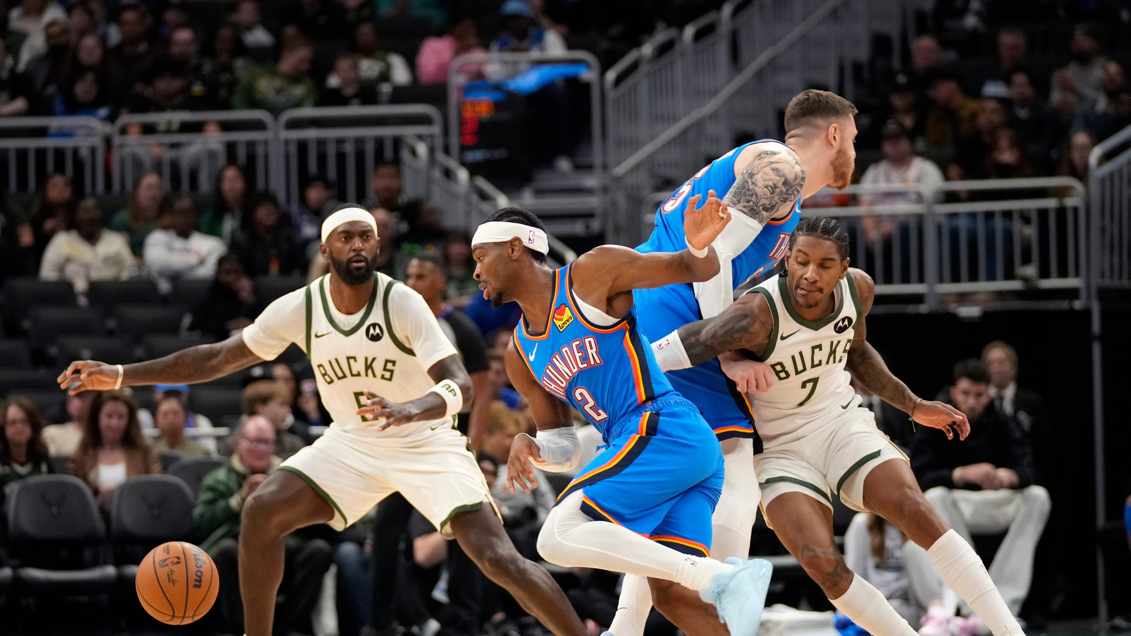 Milwaukee Bucks guard/forward Kevin Porter Jr. (7) attempts to get around Oklahoma City Thunder center Isaiah Hartenstein, second from right, as he trails behind Oklahoma City Thunder guard Shai Gilgeous-Alexander (2) as Milwaukee Bucks forward Bobby Portis (9) looks on during the first half of a preseason NBA basketball game Tuesday, Oct. 14, 2025, in Milwaukee. (AP Photo/Kayla Wolf)