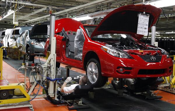 FILE - In this Nov. 10, 2008, file photo, members of a production team work on the under carriage of a Toyota Solara convertible on the assembly line at the Toyota Motor Manufacturing Kentucky plant in Georgetown, Ky. President Donald Trump’s relentless push for more manufacturing jobs has forced the auto industry into a delicate dance of contradictions. Toyota did the waltz with its long-planned announcement Monday, April 10, 2017, that it would spend $1.33 billion to retool the Kentucky factory. (AP Photo/James Crisp, File)