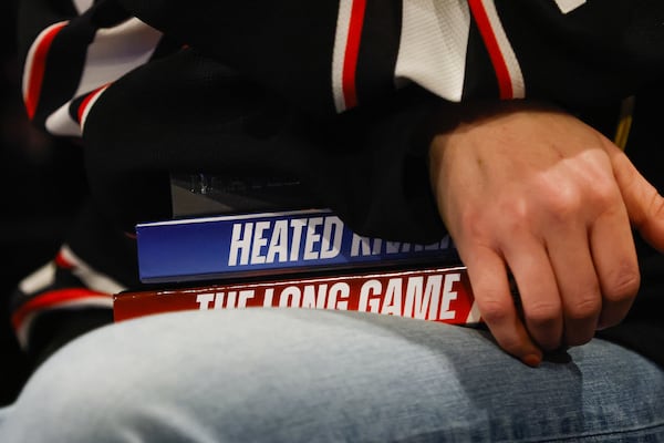 Jordan Fischer, who leads All the Tropes’ queer romance book club, holds the “Heated Rivalry” books during a gathering at All the Tropes Bookstore in Atlanta. (Abbey Cutrer/AJC)