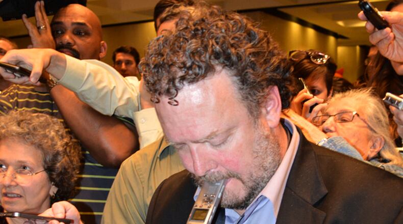 In this photo provided by the State Archives of Florida, Associated Press reporter Brendan Farrington clasps his digital recorder between his lips while using his cellphone during a press gaggle with Gov. Rick Scott on May 1, 2014, at the Florida State Capitol in Tallahassee, Fla. (Bill Cotterell/State Archives of Florida via AP)