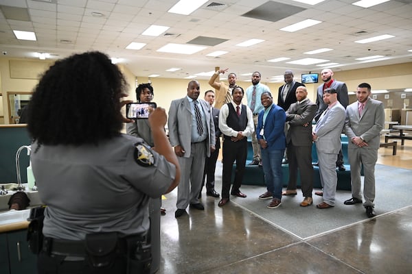 Shane Sims (center) poses with graduates as Deputy Gloria Pender (foreground) takes a group photo before their graduation ceremony for the Re-Entry Success Program at the Athens-Clarke County Jail on Wednesday, June 18, 2025, in Athens. (Hyosub Shin/AJC)