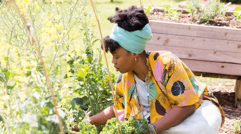 Amina Robinson, who works in customer service for an airline, tends the Habesha community garden pruning kale in the Mechanicsville neighborhood Thursday, April 9, 2020. Amina took a training class at the garden last year. “It really is coming into good use,” she said. “I need to get out here in the earth.” Jenni Girtman for The AJC