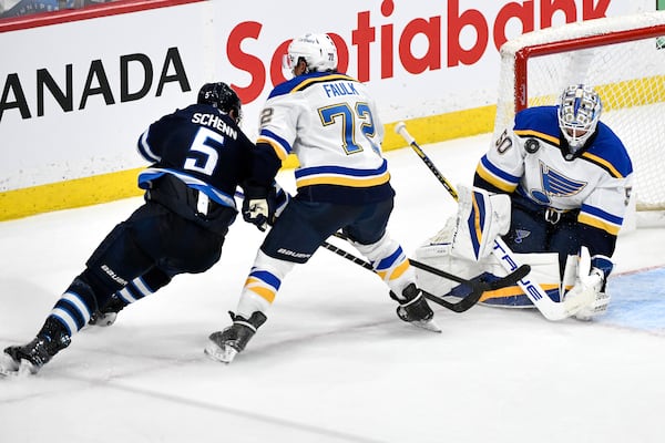 St. Louis Blues goaltender Jordan Binnington (50) makes a save against Winnipeg Jets' Luke Schenn (5) as Blues' Justin Faulk (72) defends during the third period of Game 2 of a first-round NHL hockey playoff series in Winnipeg, Manitoba, Monday April 21, 2025. (Fred Greenslade/The Canadian Press via AP)