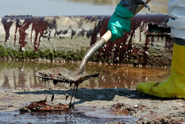 FILE - A worker shovels oil from the Deepwater Horizon oil spill off Fourchon Beach in Port Fourchon, La., May 24, 2010. (AP Photo/Patrick Semansky, File)