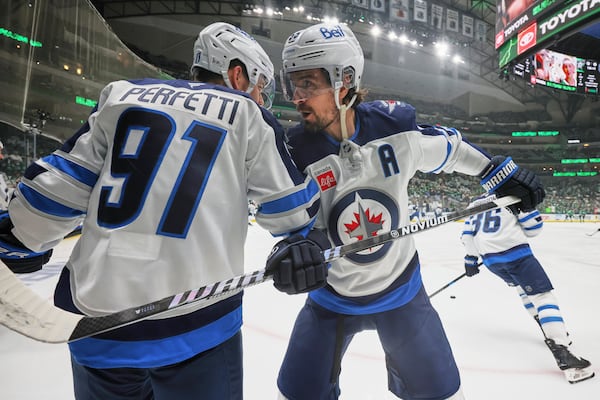 Winnipeg Jets' Cole Perfetti (91) and Mark Scheifele, right, talk during warmups before first Game 6 of a second-round NHL hockey playoff series against the Dallas Stars in Dallas, Saturday, May 17, 2025. (AP Photo/Gareth Patterson)