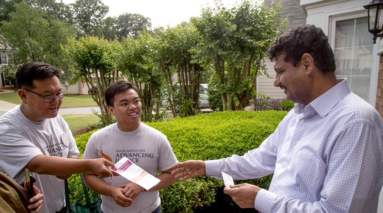 Volunteer Jongwon Lee, from left, and Asian Americans Advancing Justice program associate Raymond Partolan talk with Johns Creek homeowner Ahmed Baosman May 13 during a get-out-the-vote effort. STEVE SCHAEFER / SPECIAL TO THE AJC