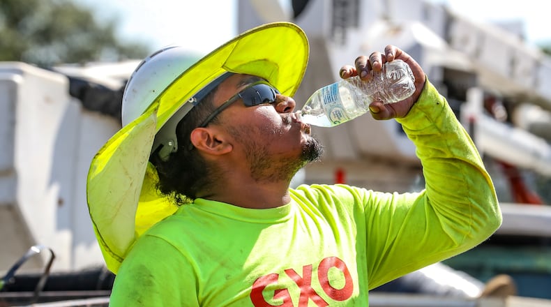 Fernando Rosales with RJH Electrical Contractors worked on installing an electrical box on Northside Drive near I-75 gets hydrated during the oppressive heat in metro Atlanta on Monday, Aug. 14, 2023. (John Spink / John.Spink@ajc.com)