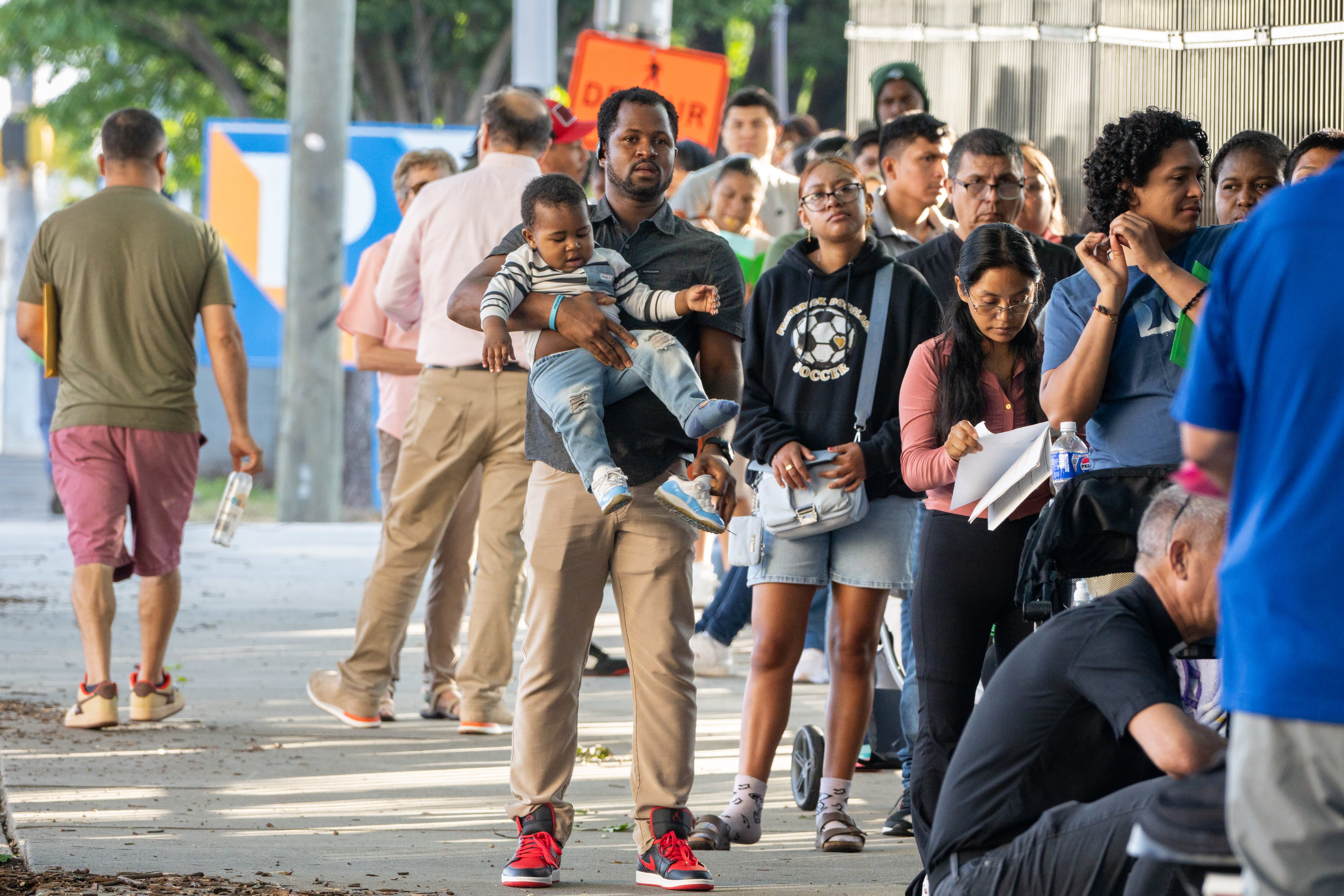 People line up and wait along Ted Turner Drive outside the Immigration and Customs Enforcement Atlanta Field office.Thursday, July 10, 2025. (Ben Hendren for the AJC)