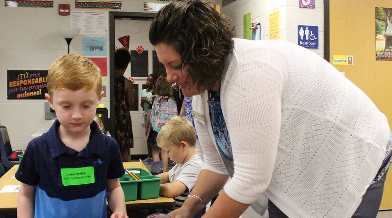 Emily Costine, a kindergarten teacher at Level Creek Elementary School, helps her student, Leland Griffin, get in his seat during the first day of school at Level Creek Elementary School on August 6, 2020. Costine teaches one of the dual language immersion classes. Gwinnett County Public Schools is offering signing bonuses to bilingual teachers. Jenna Eason / Jenna.Eason@coxinc.com