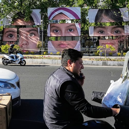 Vehicles drive past banners showing portraits of the school children who were killed during a strike on a school in southern town of Minab on Feb. 28, at Tajrish square in northern Tehran, Iran, Sunday, May 10, 2026. (AP Photo/Vahid Salemi)