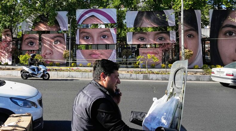 Vehicles drive past banners showing portraits of the school children who were killed during a strike on a school in southern town of Minab on Feb. 28, at Tajrish square in northern Tehran, Iran, Sunday, May 10, 2026. (AP Photo/Vahid Salemi)