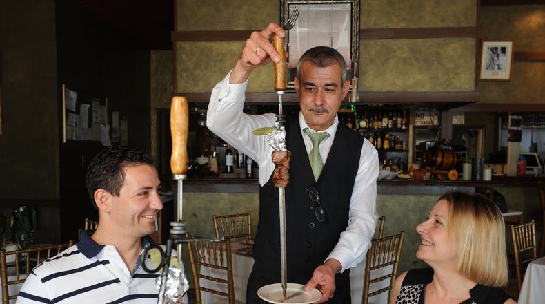 Waiter Jorge Silva serves regular customers Regina and Carlos Mendes at Emidio's in Sandy Springs. (Beckysteinphotography.com)