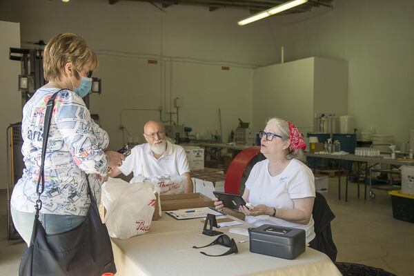 Betsey Dahlberg (right) and Paul (center) Allen, owners of Hope Springs Distillery, with Darlene Stokan (left), who purchased four bottles of their hand sanitizer, produced at their distillery in downtown Lilburn. (ALYSSA POINTER / ALYSSA.POINTER@AJC.COM)