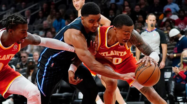 Orlando's Chuma Okeke battles John Collins of the Hawks while Delon Wright reaches in during the first half of Monday's game at State Farm Arena. (AP Photo/John Bazemore)