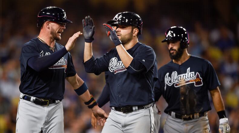 CORRECTS PLAYER AT LEFT TO TYLER FLOWERS, INSTEAD OF ENDER INCIARTE - Atlanta Braves' Jaime Garcia, center, celebrates with Tyler Flowers, left, after hitting a grand slam off Los Angeles Dodgers starting pitcher Alex Wood, as Sean Rodriguez trails during the fifth inning of a baseball game in Los Angeles, Friday, July 21, 2017. (AP Photo/Kelvin Kuo)