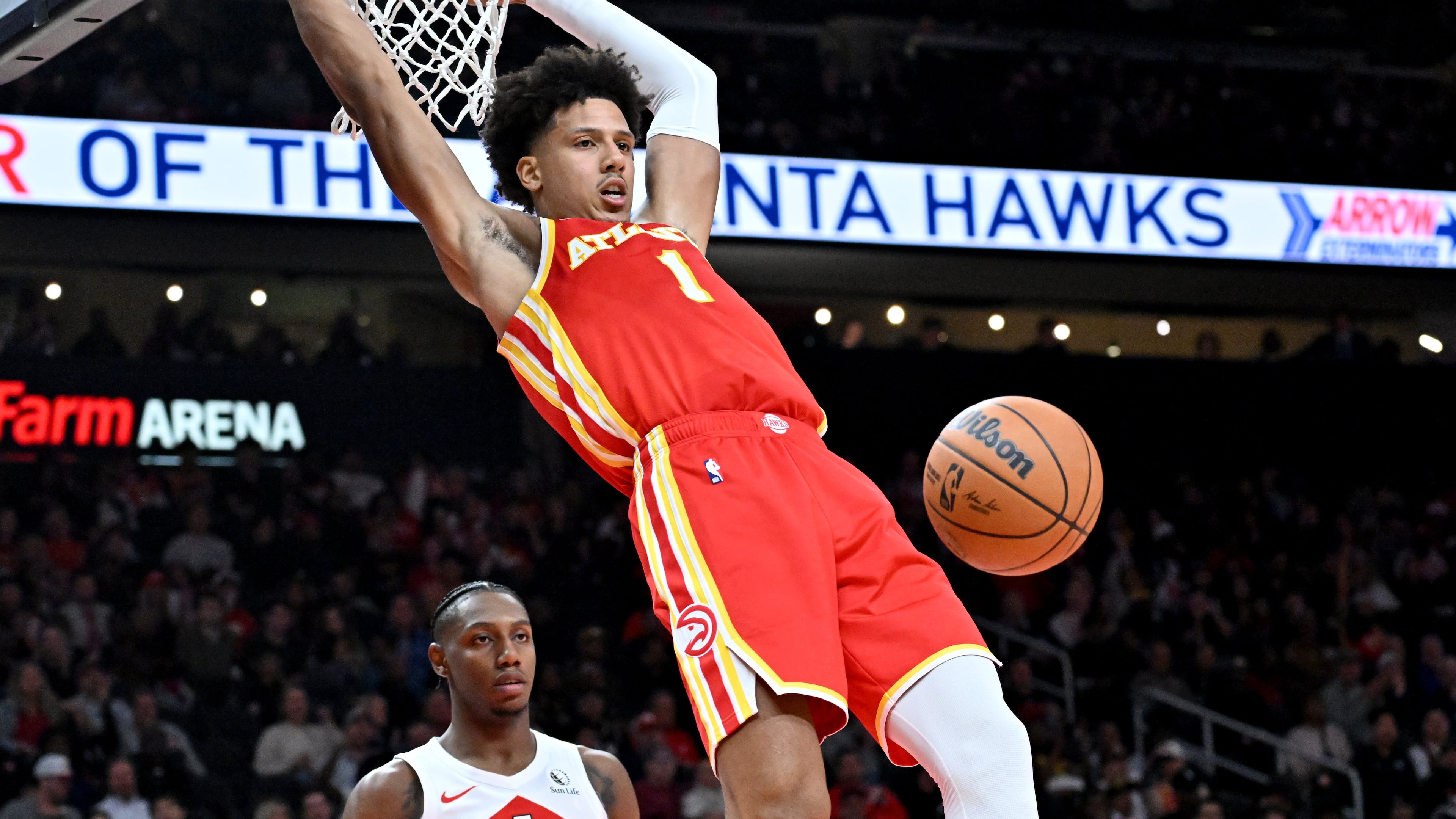 Atlanta Hawks forward Jalen Johnson (1) hangs on the basket after dunking the ball during the second half in the home opener at State Farm Arena, Wednesday, October 22, 2025, in Atlanta. Toronto Raptors won 138-118 over Atlanta Hawks. (Hyosub Shin/AJC)
