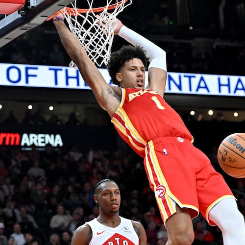 Atlanta Hawks forward Jalen Johnson (1) hangs on the basket after dunking the ball during the second half in the home opener at State Farm Arena, Wednesday, October 22, 2025, in Atlanta. Toronto Raptors won 138-118 over Atlanta Hawks. (Hyosub Shin/AJC)