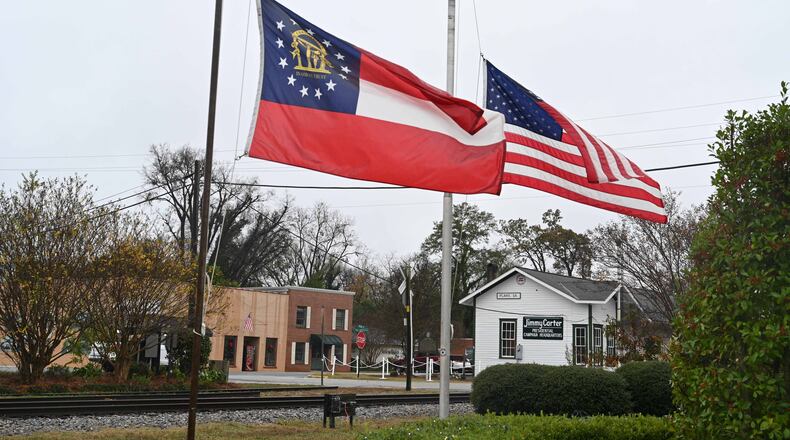 The American and Georgia state flags fly at half mast in honor of Rosalynn Carter in downtown Plains on Tuesday. She was 96 years old. (Hyosub Shin / Hyosub.Shin@ajc.com)