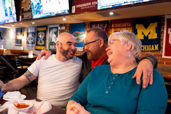 Bartender Dan Bergman, center, greets Kevin Gilliam and Joy Ivemeyer as the Woofs Sports Bar regulars sit at the bar. (Ben Gray for the AJC)