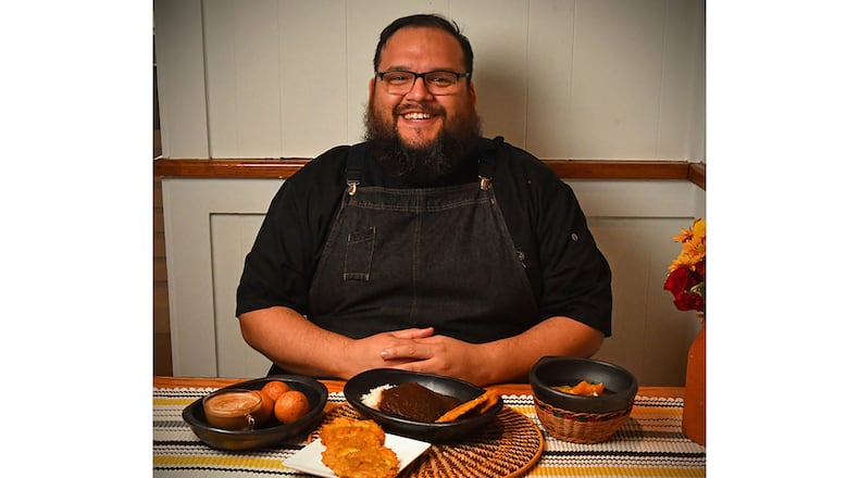 Atlanta chef Christian Lopez of Humo Cuisine shows some of his Colombian dishes: (from left) Colombian Buñuelos with coffee, Fried Green Plantains, Posta Negra Cartagenera (beef roast in the manner of the city of Cartagena), served with rice and Fried Green Plantains, and Chuyaco (navel orange salad). (Styling by Christian Lopez / Chris Hunt for the AJC)