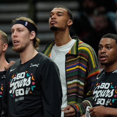 San Antonio Spurs forward Victor Wembanyama, center, wears street cloths on the bench as he sits out Game 3 of a first-round NBA playoffs basketball series against the Portland Trail Blazers in Portland, Ore, Friday, April 24, 2026. (AP Photo/Jenny Kane)