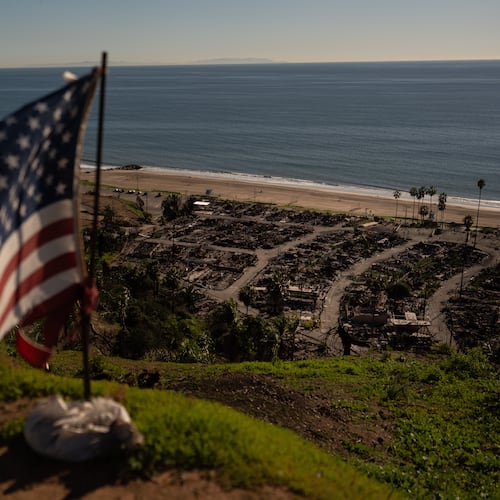 FILE - A tattered U.S. flag flaps in the wind over the remains of a mobile home park that was destroyed in the Palisades Fire along the Pacific Ocean, Dec. 5, 2025, in the Pacific Palisades neighborhood of Los Angeles. (AP Photo/Jae C. Hong, file)