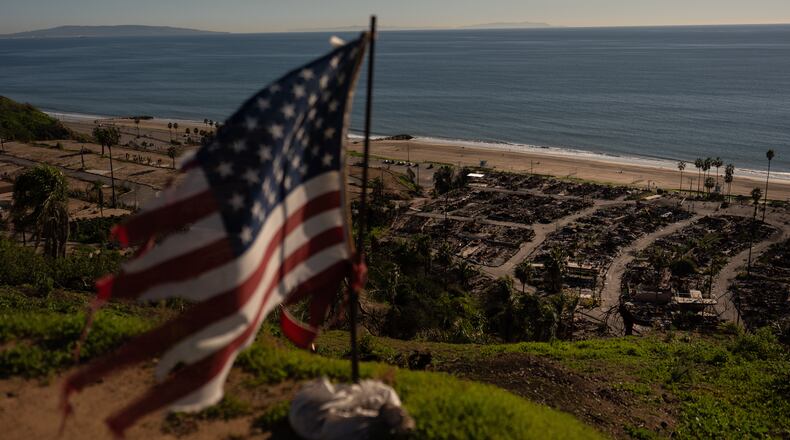 FILE - A tattered U.S. flag flaps in the wind over the remains of a mobile home park that was destroyed in the Palisades Fire along the Pacific Ocean, Dec. 5, 2025, in the Pacific Palisades neighborhood of Los Angeles. (AP Photo/Jae C. Hong, file)